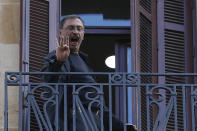 An unidentified man standing on the balcony of a bank headquarters, gestures with his middle finger to Lebanese protesters in Beirut, Lebanon, Friday, Sept. 24, 2021. Dozens of Lebanese depositors protested throwing eggs and tomatoes on a number of private banks in central Beirut, demanding to have access to their deposits which have been blocked under informal capital controls since the country's financial and economic crisis began in late 2019. (AP Photo/Hussein Malla)