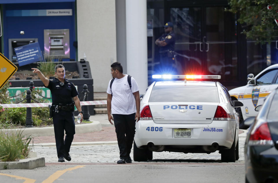 <p>A police officer directs a pedestrian away from a blocked-off area near the scene of a mass shooting at Jacksonville Landing in Jacksonville, Fla., Aug. 26, 2018. (Photo: John Raoux/AP) </p>