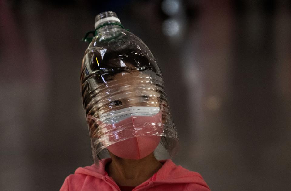 A Chinese girl wears a plastic bottle as makeshift homemade protection and a protective mask while waiting to check in to a flight at Beijing Capital Airport on Jan. 30, 2020 in Beijing, China.