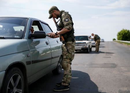 Ukrainian servicemen check cars at a checkpoint near Slaviansk in Donetsk region, Ukraine, June 29, 2016. Picture taken June 29, 2016. To match Insight UKRAINE-CRISIS/ARMS REUTERS/Gleb Garanich