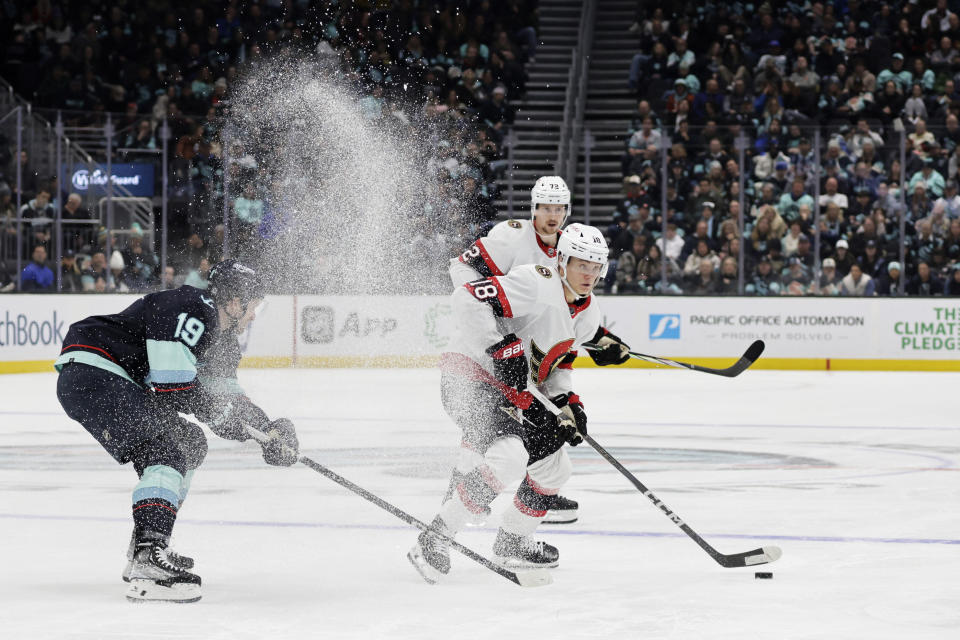 Ottawa Senators center Tim Stutzle (18) works to control the puck with Seattle Kraken left wing Jared McCann (19) defending on the right during the second period of an NHL hockey game, Thursday, Jan. 4, 2024, in Seattle. (AP Photo/John Froschauer)