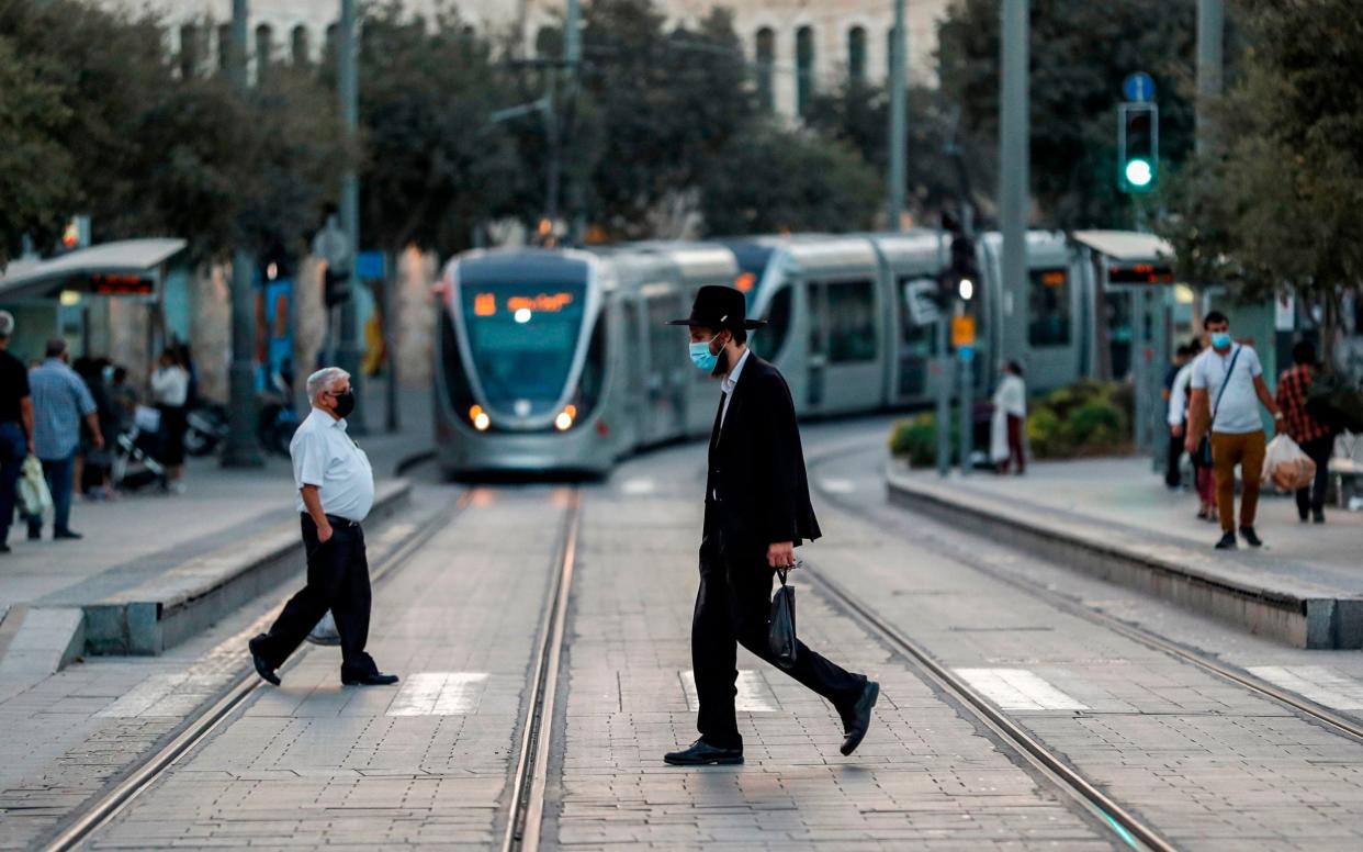 An Orthodox Jewish man, mask-clad due to the COVID-19 coronavirus pandemic, crosses a street in Jerusalem - AFP