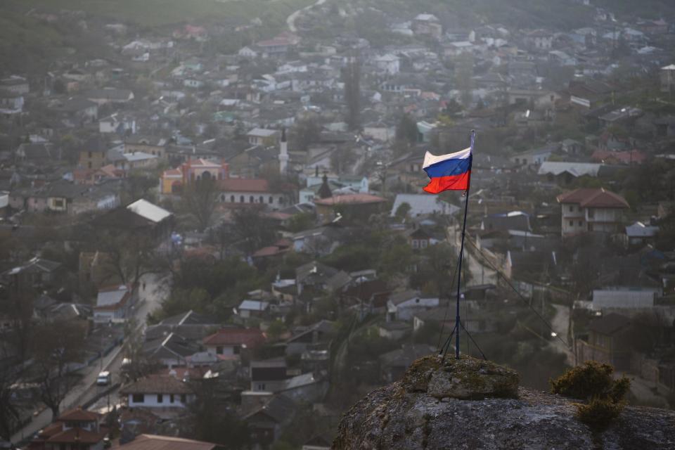 A Russian national flag flies on a hilltop near the city of Bakhchysarai, Crimea, Friday March 28, 2014, where the Crimean Tatar Qurultay, a religious congress, will take place Saturday.The Crimean Tatar Qurultay, a religious congress, will determine whether the Tatars will accept Russian citizenship and the political system that comes with it, or remain Ukrainian citizens on Russian soil. (AP Photo/Pavel Golovkin)