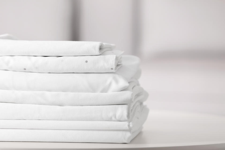 New clean folded bed linens on table indoors.