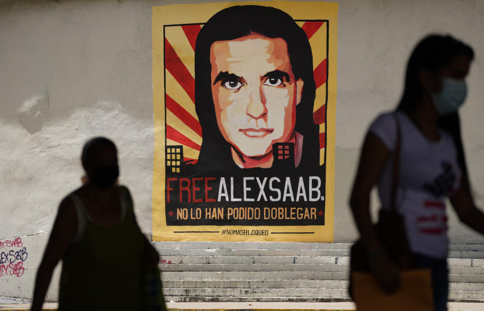 FILE - Pedestrians walk near a poster asking for the freedom of Colombian businessman and Venezuelan special envoy Alex Saab, in Caracas, Venezuela, Sept. 9, 2021. Saab’s attorneys filed a new motion on Oct. 17, 2022 to dismiss criminal charges, arguing once again that he was illegally abducted on U.S. orders while traveling as a diplomat to Iran. Saab was arrested in Cape Verde in June 2020, and extradited to the U.S to face charges in Oct. 2021. (AP Photo/Ariana Cubillos, File)