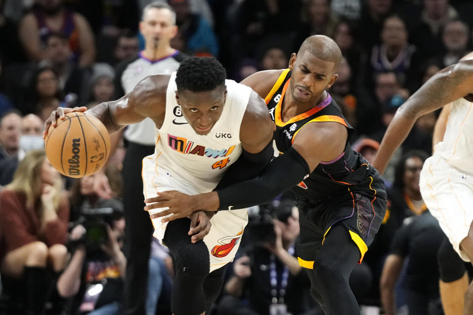 Phoenix Suns guard Chris Paul, right, fouls Miami Heat guard Victor Oladipo (4) during the first half of an NBA basketball game in Phoenix, Friday, Jan. 6, 2023. (AP Photo/Ross D. Franklin)