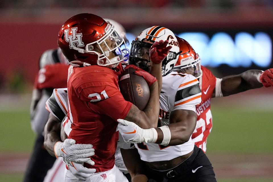 Houston running back Stacy Sneed (21) is hit by Oklahoma State safety Nick Session (14) while returning a kick during the second half of an NCAA college football game Saturday, Nov. 18, 2023, in Houston. Oklahoma State won 43-30. (AP Photo/David J. Phillip)