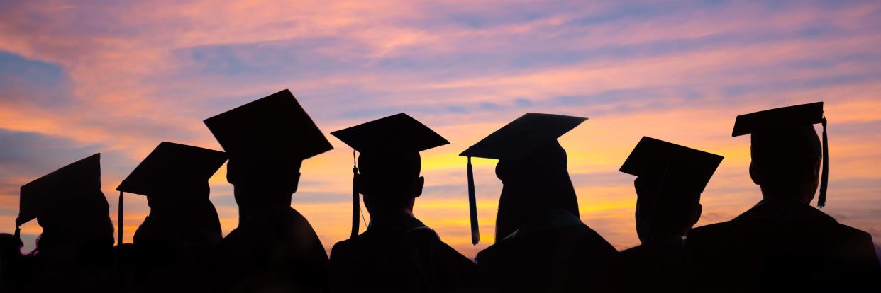 Silhouettes of students with graduate caps in a row.