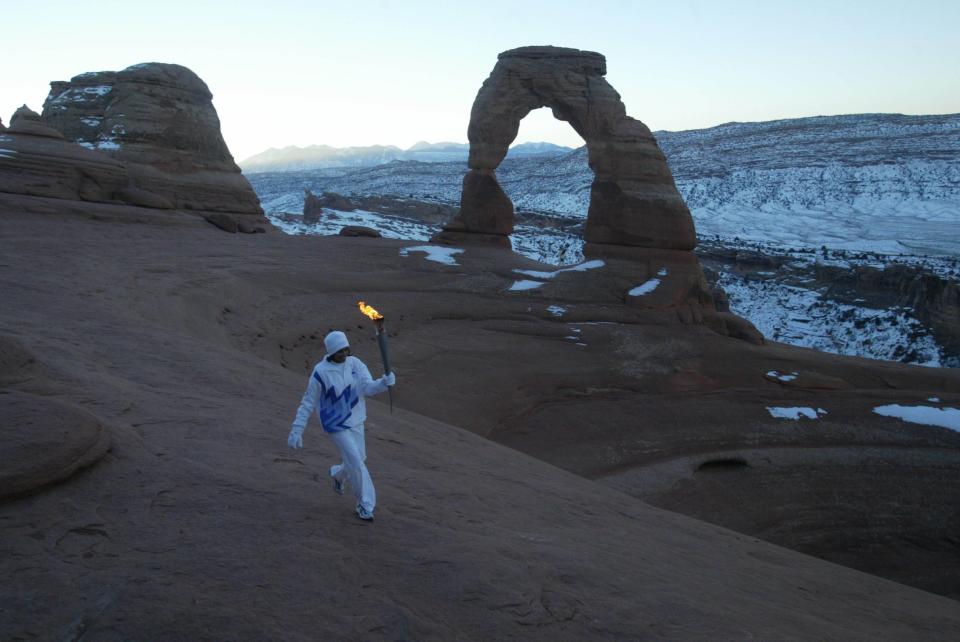 Native American Stephanie Laree Spann walks the Olympic torch past Delicate Arch in Arches National Park near Moab on Feb. 2, 2002. | Tom Smart, Deseret News