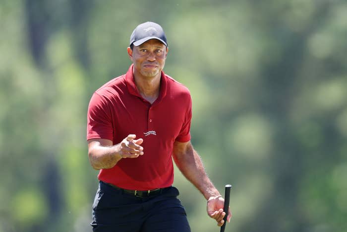 Golfer in action wearing a red shirt and cap, holding a putter on a sunny day; identity undisclosed