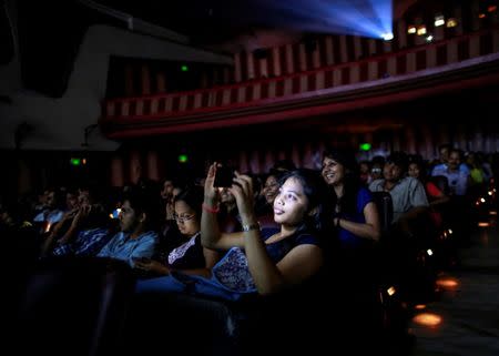 A cinema goer takes a picture as others watch "Dilwale Dulhania Le Jayenge" starring actor Shah Rukh Khan, inside Maratha Mandir theatre in Mumbai int his file photo dated December 12, 2014. REUTERS/Danish Siddiqui