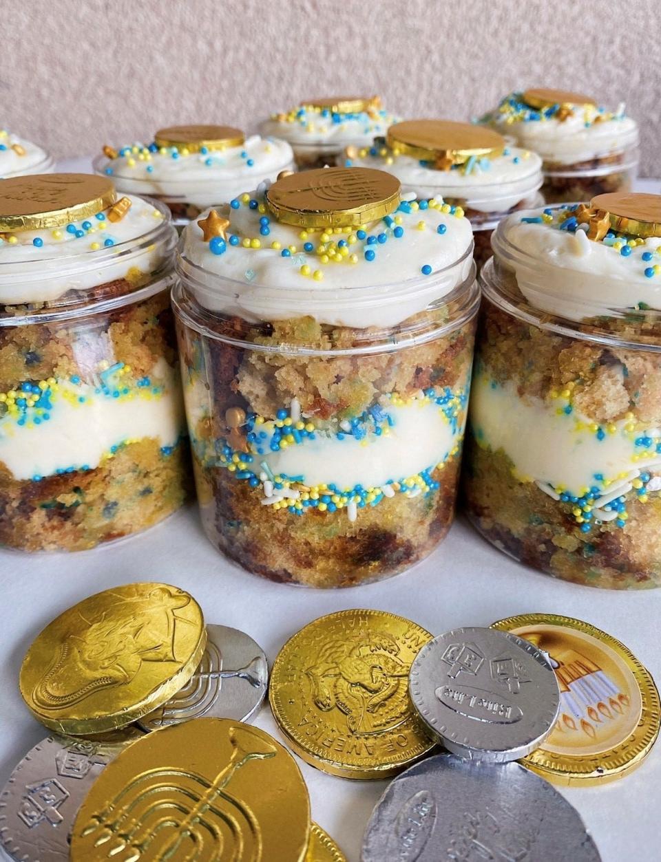 Gold & Gelt Cake in a Jar from Andie's Eats is a Hanukkah themed vanilla cake layered vanilla frosting, blue and yellow sprinkles, topped with Hanukkah gelt.