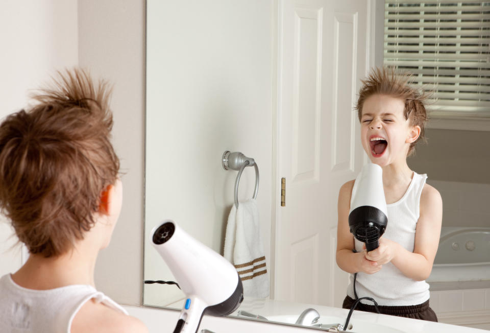 A 6 year old boy pretending that his hair dryer is a microphone.