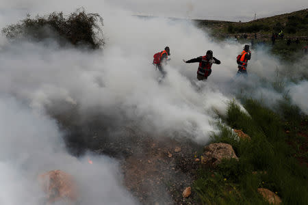 Medics run away from tear during clashes between Palestinians and Israeli troops at a protest marking the Land Day, in al-Mughayer village in the Israeli-occupied West Bank March 29, 2019. REUTERS/Mohamad Torokman