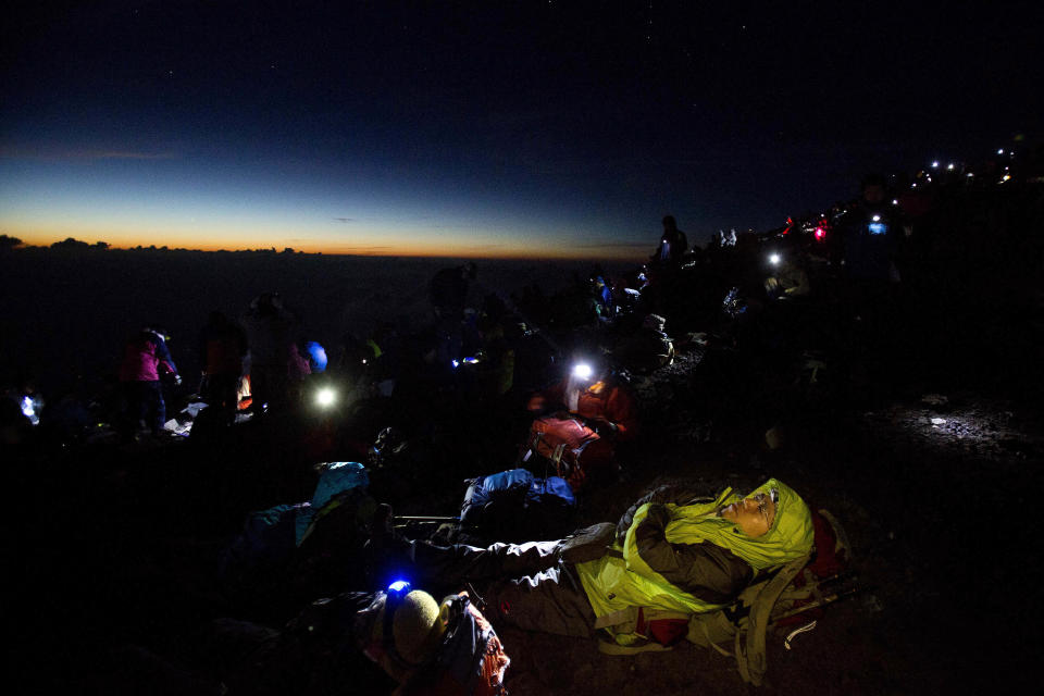 In this Aug. 11, 2013 photo, thousands of hikers wait for the sun to rise on the summit of Mount Fuji before dawn. The recent recognition of the 3,776-meter (12,388-foot) peak as a UNESCO World Heritage site has many here worried that will draw still more people, adding to the wear and tear on the environment from the more than 300,000 who already climb the mountain each year. (AP Photo/David Guttenfelder)