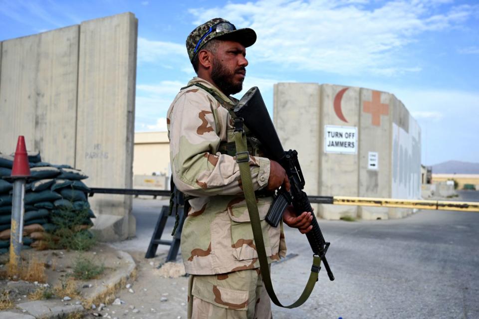 Armed Afghan soldier stands guard at a gate