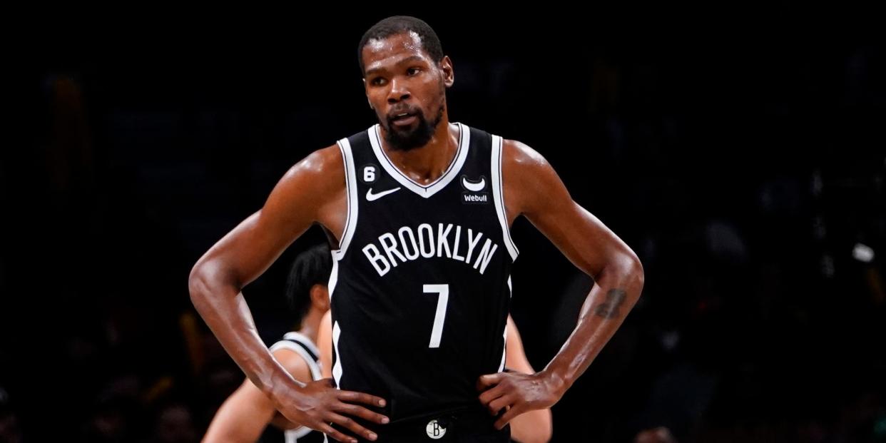 Kevin Durant stands with his hands on his hips and looks to the side during a Nets game.