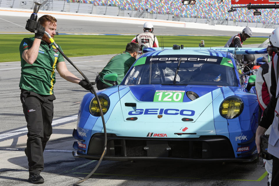 The Wright Motorsports Porsche 911 crew makes adjustments to the car on pit road during a practice session for the Rolex 24 hour auto race at Daytona International Speedway, Thursday, Jan. 25, 2024, in Daytona Beach, Fla. The car will also double for a car that will appear in an upcoming movie starring actor Brad Pitt. (AP Photo/John Raoux)