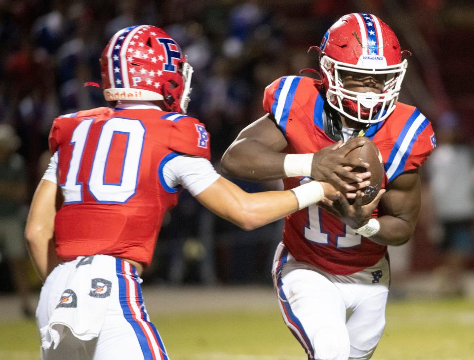 Pace quarterback Nick Simmons (No. 10) hands off to running back Ben Tyner (No. 10) during Friday night's District 1-4S game against Navarre.