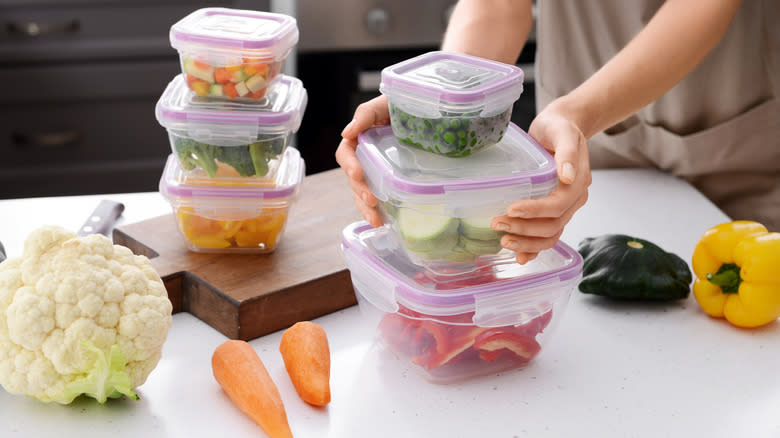 person stacking veggies in plastic containers