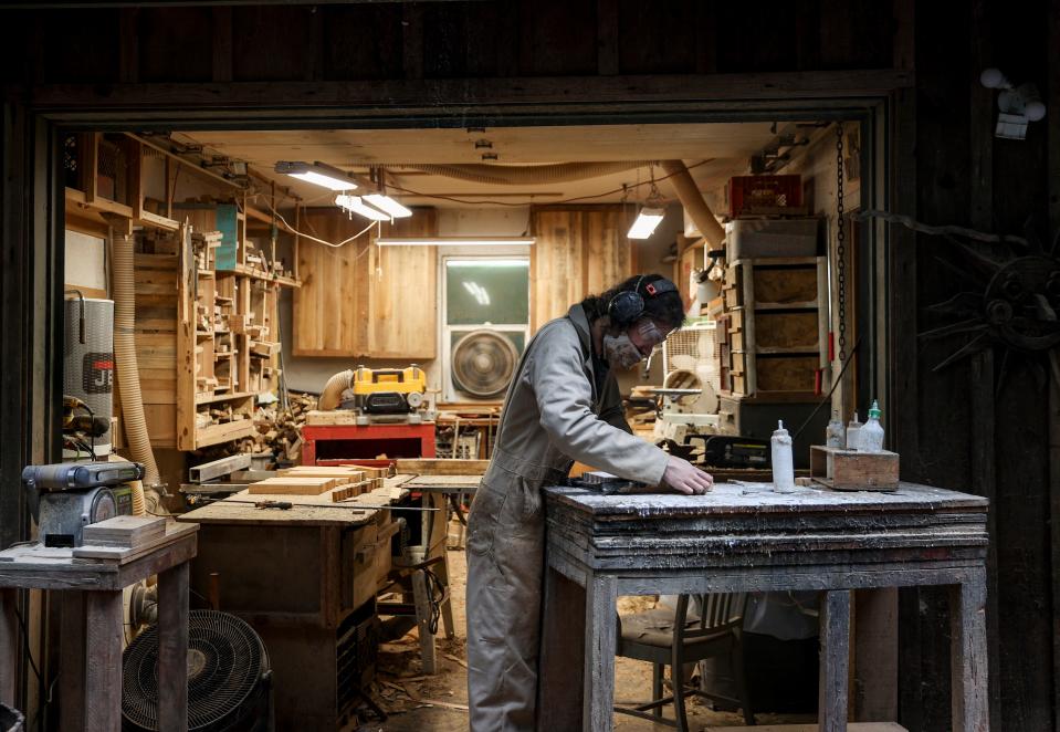 Reeve Carter glues wood together and uses a clamp to secure the pieces of what will eventually become a cutting board or bowl.