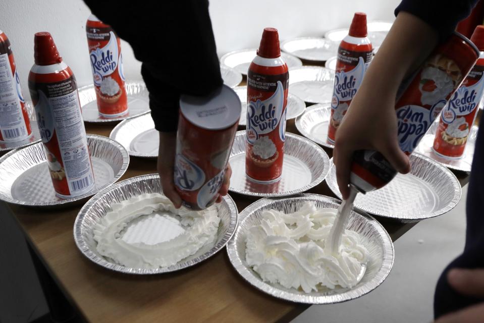 FILE - Students prepare whipped cream pies before a celebration of pi at the Hamtramck Academy Tuesday, March 14, 2017, in Hamtramck, Mich. On Friday, Sept. 2, 2022, The Associated Press reported on stories circulating online incorrectly claiming a New York law that aims to crack down on nitrous oxide abuse makes it illegal for anyone under age 21 to purchase a can of whipped cream. (AP Photo/Carlos Osorio, File)