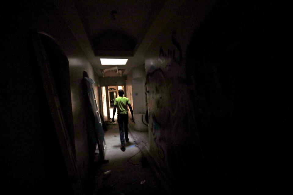 A man walks in a darkened hallway