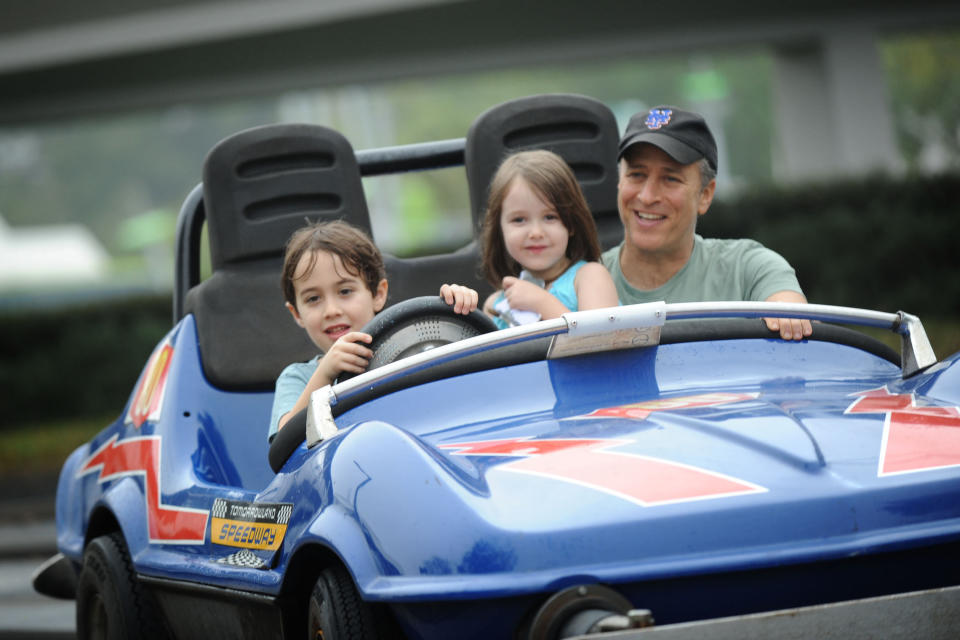 LAKE BUENA VISTA, FL - FEBRUARY 04:  In this handout photo provided by Disney, Emmy Award-winning TV host and Grammy Award-winning comedian Jon Stewart takes a ride on the Tomorrowland Indy Speedway with his children Nate (left, age 6) and Maggie (center, age 5) at the Magic Kingdom theme park on February 4, 2011 in Lake Buena Vista, Florida.  The February 4 visit took place on Maggie's 5th birthday, and Stewart and his family celebrated the occasion with friends at the Walt Disney World theme park.  (Photo by David Roark/Disney via Getty Images)
