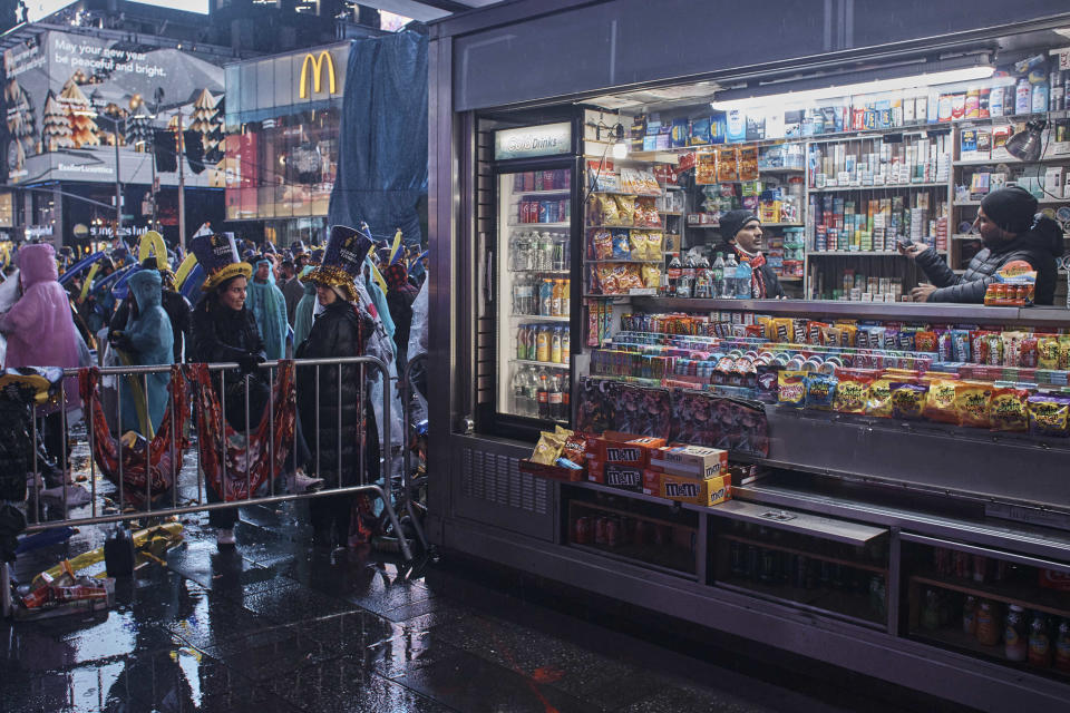 People talk inside a shop as revelers wait for the countdown during the New Year's Eve celebrations in Times Square on Saturday, Dec. 31, 2022, in New York. (AP Photo/Andres Kudacki)