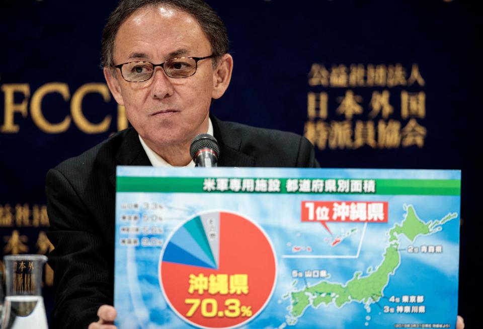 Okinawa Governor Denny Tamaki shows a board, displaying statistics of U.S. military bases in Japan including Okinawa, during a press conference in Tokyo on March 1, 2019, after a vote on the relocation of a U.S. base on the island. / Credit: BEHROUZ MEHRI/AFP/Getty
