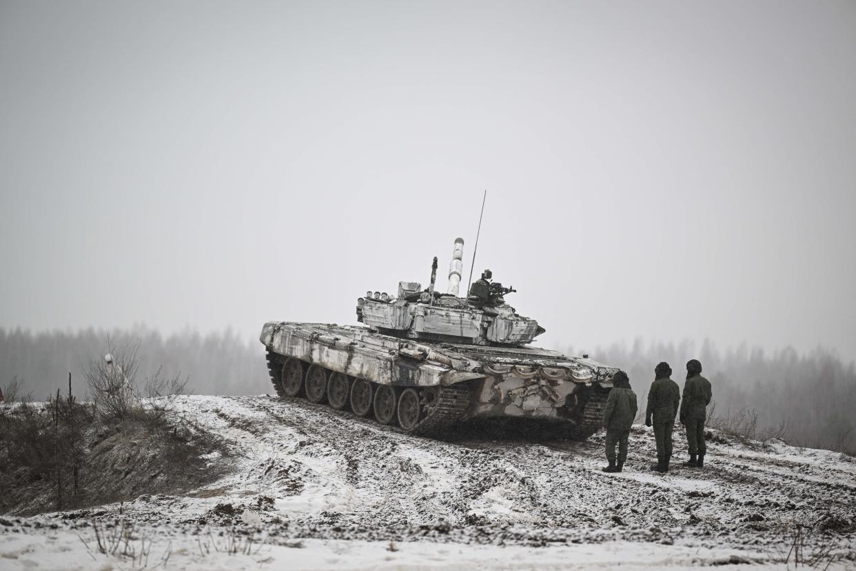 Three cadets of the Military Academy of the Republic of Belarus stand by a tank at the Belaya Luzha training center.