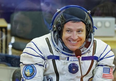 The International Space Station (ISS) crew member Jack Fischer of the U.S. talks to his family members as they are reflected in a glass between them after space suit check at the Baikonur cosmodrome, Kazakhstan April 20, 2017. REUTERS/Shamil Zhumatov