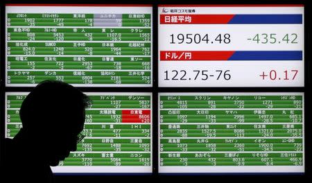 A man walks past an electronic board showing Japan's Nikkei average (top of upper right screen) and the Japanese yen's exchange rate against against the U.S. dollar outside a brokerage in Tokyo, Japan, December 4, 2015. REUTERS/Toru Hanai