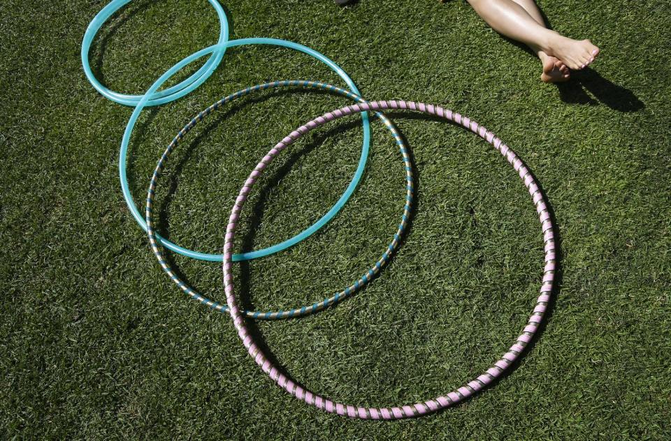 In this Oct. 2, 2013, picture, Liz Pereria relaxes on a Balboa Park lawn alongside her hula hoops in San Diego. Balboa Park will be marking its 100th anniversary in 2015 with a host of festivities, although any day is worth a visit to the 1,200-acre urban oasis that rivals New York’s Central Park and is home to the San Diego Zoo. (AP Photo/Gregory Bull)