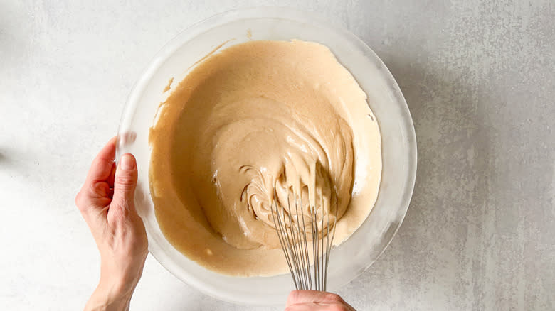 Whisking cinnamon-cashew frosting in bowl on counter top
