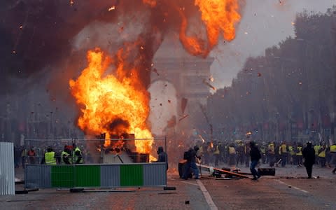 A fire rages as men wearing yellow vests protest against rising fuel prices on the Champs-Elysees - Credit:  Getty 