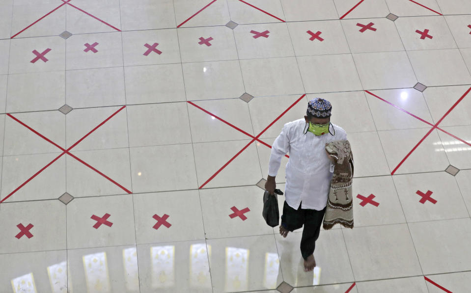 A Muslim walks across marks used to space worshippers apart as a precaution against the coronavirus after Friday prayer at the Al Barkah Grand Mosque in Bekasi on the outskirts of Jakarta, Indonesia, Friday, May 29, 2020. Muslims in some parts of Indonesia attended Friday prayers as mosques closed by the coronavirus for weeks were allowed to start reopening in the world's most populous Muslim nation. (AP Photo/Achmad Ibrahim)