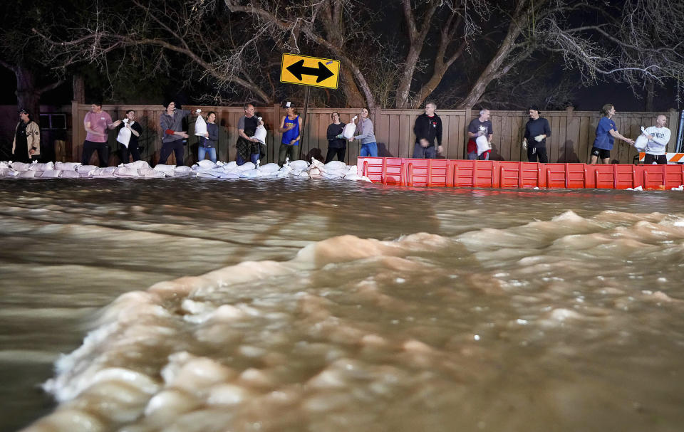 People work to protect homes into the night along 1700 South in Salt Lake City from the rising flow of Emigration Creek through Wasatch Hollow Park on Wednesday, April 12, 2023. As rapid snowmelt and possible April showers stoke fears of heavy flooding in the Northern Plains, state officials are announcing flood response plans, and residents are assembling thousands — if not hundreds of thousands — of sandbags to combat floods themselves. (Francisco Kjolseth/The Salt Lake Tribune via AP)