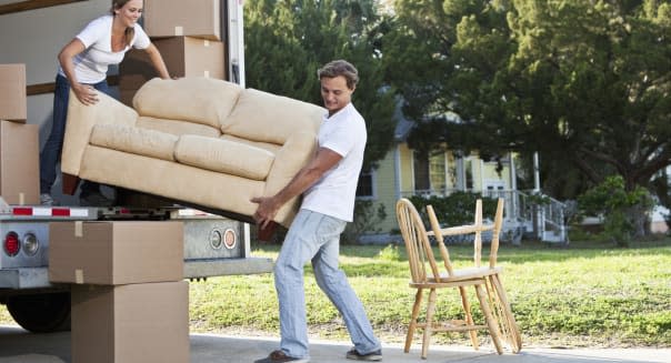 'Couple moving house, loading or unloading couch in moving van'