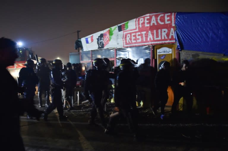 Anti-riot police walk past a restaurant as they patrol the Calais "Jungle" camp on October 25, 2016