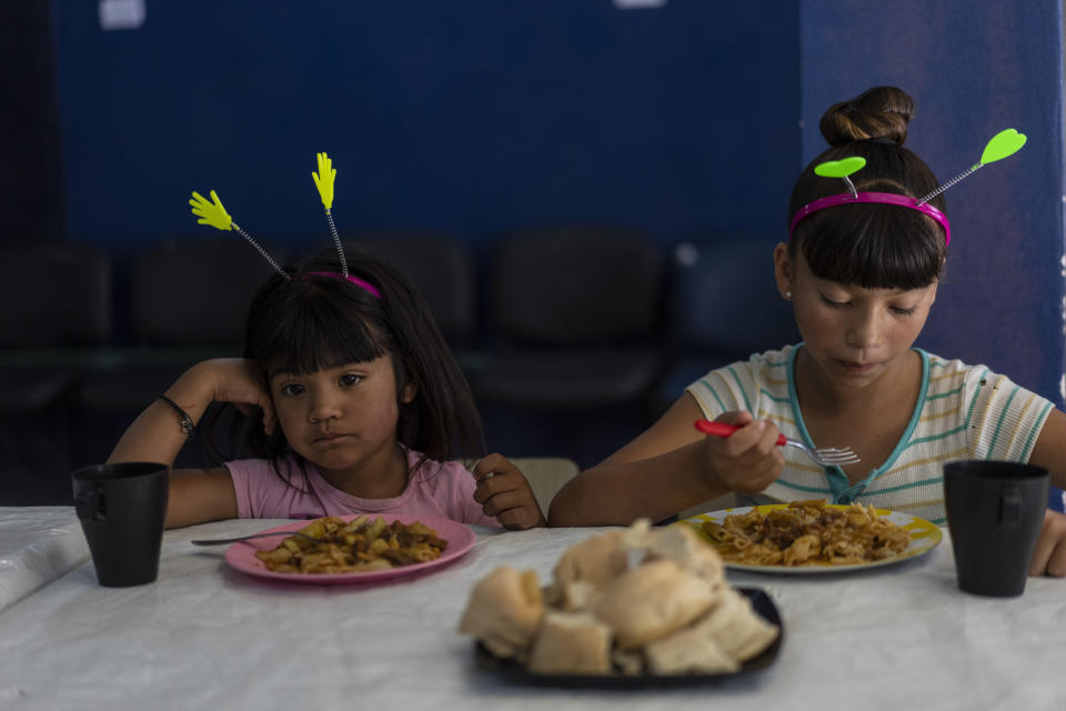 Las hermanas Aleai Fries, de 12 años, a la derecha, y Naomi, de 5, almuerzan en el comedor social "Los Amigos" en Buenos Aires, Argentina, el martes 15 de noviembre de 2022. (AP Foto/Rodrigo Abd)