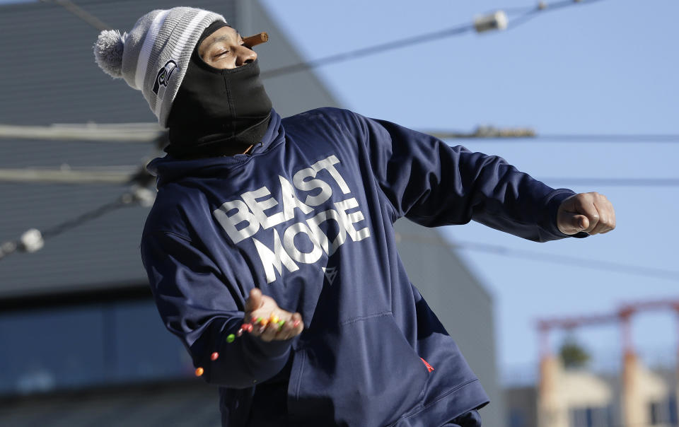 Seattle Seahawks' running back Marshawn Lynch throws pieces of Skittles candy while riding on the hood of a vehicle during the Super Bowl champions parade on Wednesday, Feb. 5, 2014, in Seattle. The Seahawks beat the Denver Broncos 43-8 in NFL football's Super Bowl XLVIII on Sunday. (AP Photo/Elaine Thompson)