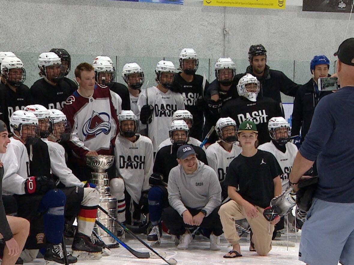 Members of DASH hockey development program post with the Colorado Avalanche's and Cale Makar and the Stanley Cup at Calgary's Crowchild Twin Arenas on Thursday. (Rebecca Kelly/CBC - image credit)