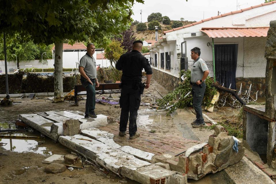 Officers of the Guardia Civil stand amidst rubbles on Monday in the town of Aldea del Fresno, in the Madrid region as a man was reported missing after his vehicle was swept away by an overflowing river during heavy rains.