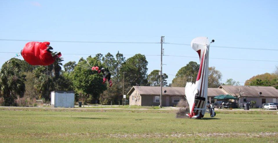 This photo released by the Polk County Sheriff's Office shows a plane nose-diving into the ground after getting tangled with a parachutist, left, Saturday March 8, 2014, at the South Lakeland Airport in Mulberry, Fla. Both the pilot and jumper hospitalized with minor injuries. (AP Photo/Polk County Sheriff's Office, Tim Telford) MANDATORY CREDIT