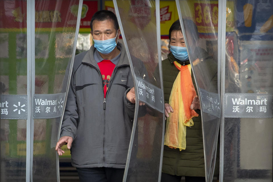 Dos personas con mascarillas salen de una tienda Walmart en Beijing, el sábado 1 de febrero de 2020. La cifra de muertos por un nuevo virus en China ha aumentado a 259 y un funcionario de la Organización Mundial de la Salud dice que otros gobiernos deben prepararse controlar "brotes locales" si la enfermedad se propaga. (AP Foto/Mark Sjefeelbein)