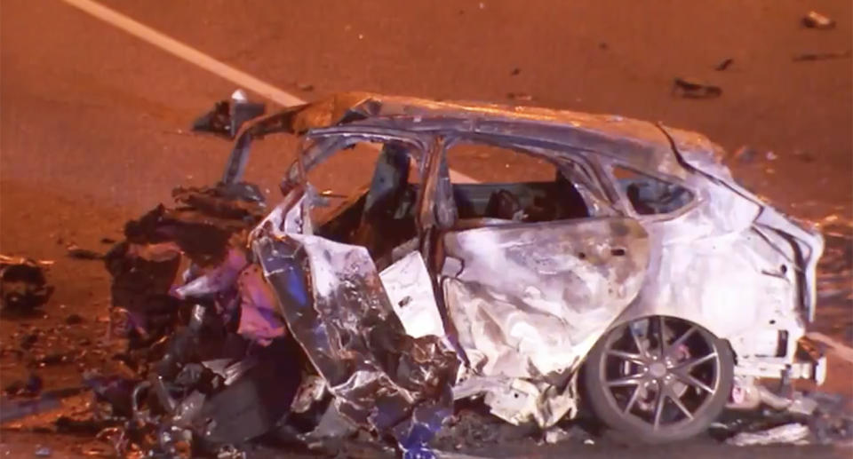 A car wreckage on the road at night.