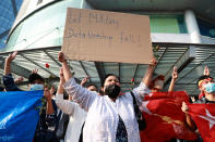 A female protester holds up a cardboard sign which says "Let Military Dictatorship Fall!" outside the Hledan Center in Yangon, Myanmar on Sunday, Feb. 7, 2021. Thousands of people rallied against the military takeover in Myanmar's biggest city on Sunday and demanded the release of Aung San Suu Kyi, whose elected government was toppled by the army that also imposed an internet blackout. (AP Photo)