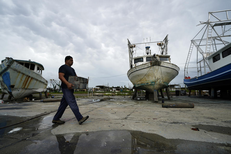 Mike Bartholemey places extra blocks under his recently dry docked shrimp boat, out of concern for strong winds, in Empire, La., Sunday, Aug. 23, 2020, in advance of Hurricane Marco, expected to make landfall on the Southern Louisiana coast. (AP Photo/Gerald Herbert)