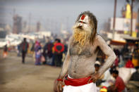 A Hindu holy man watches pilgrims walk past during Magh Mela festival, in Prayagraj, India. Tuesday, Feb.16, 2021. Millions of people have joined a 45-day long Hindu bathing festival in this northern Indian city, where devotees take a holy dip at Sangam, the sacred confluence of the rivers Ganga, Yamuna and the mythical Saraswati. Here, they bathe on certain days considered to be auspicious in the belief that they be cleansed of all sins. (AP Photo/Rajesh Kumar Singh)